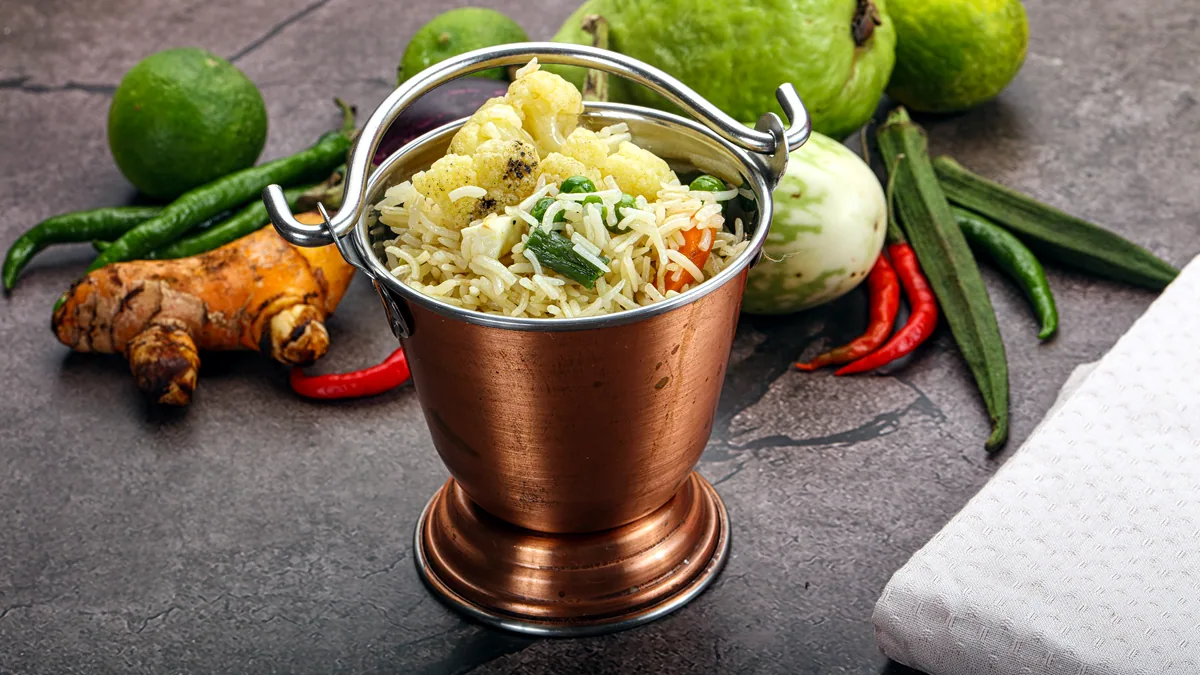 Long grain basmati rice steaming in a polished copper pot.