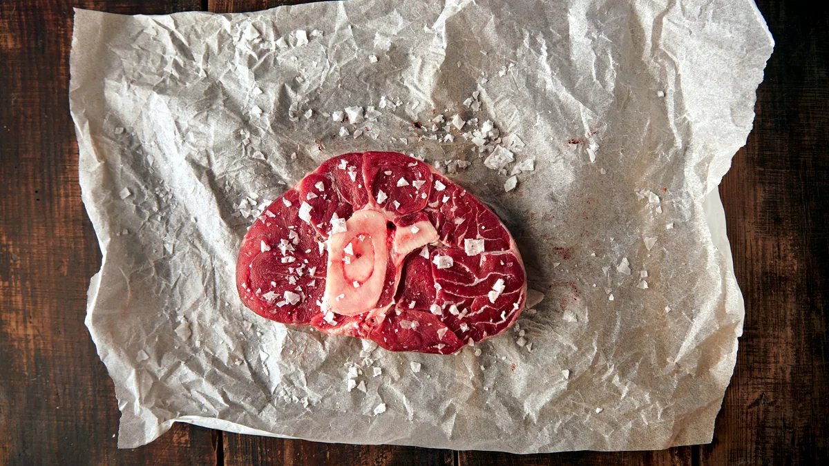A raw venison steak resting on crinkled butcher paper, ready for the kitchen.