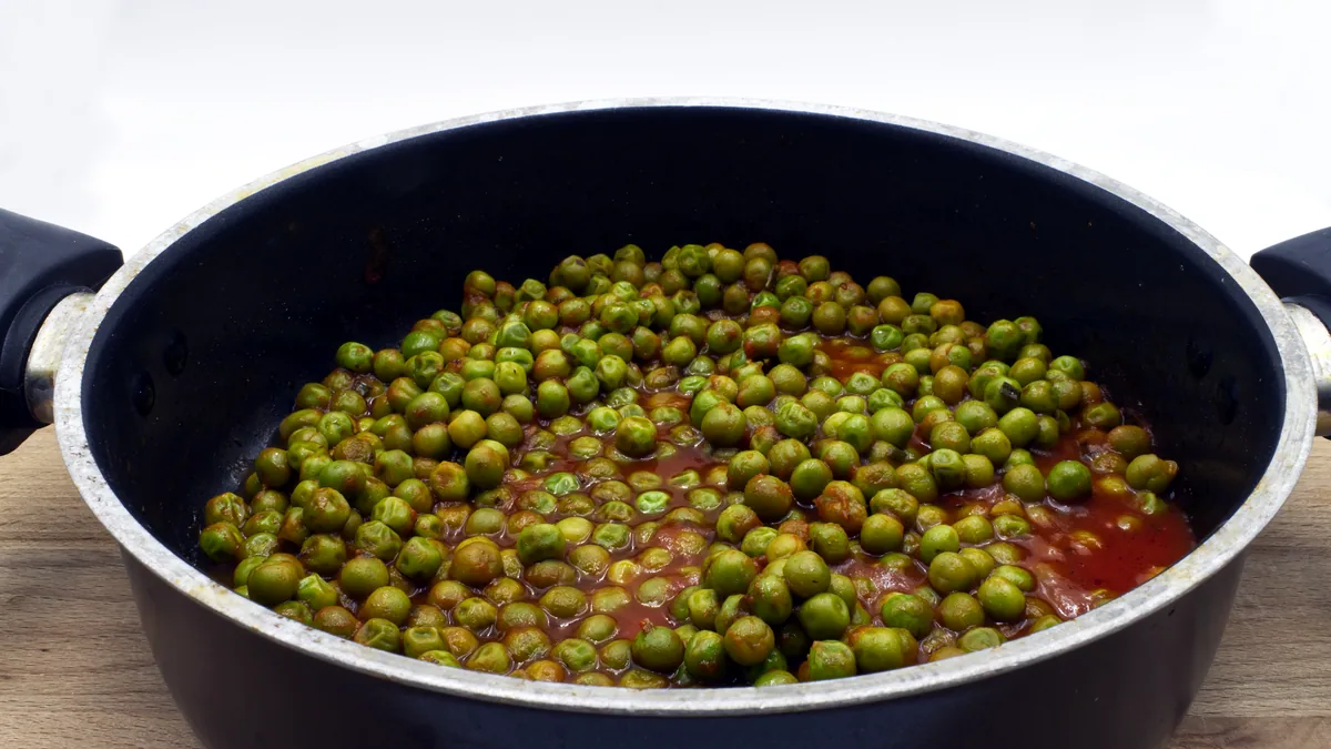 Green lentils bubbling gently in a stainless steel saucepan on the stove.